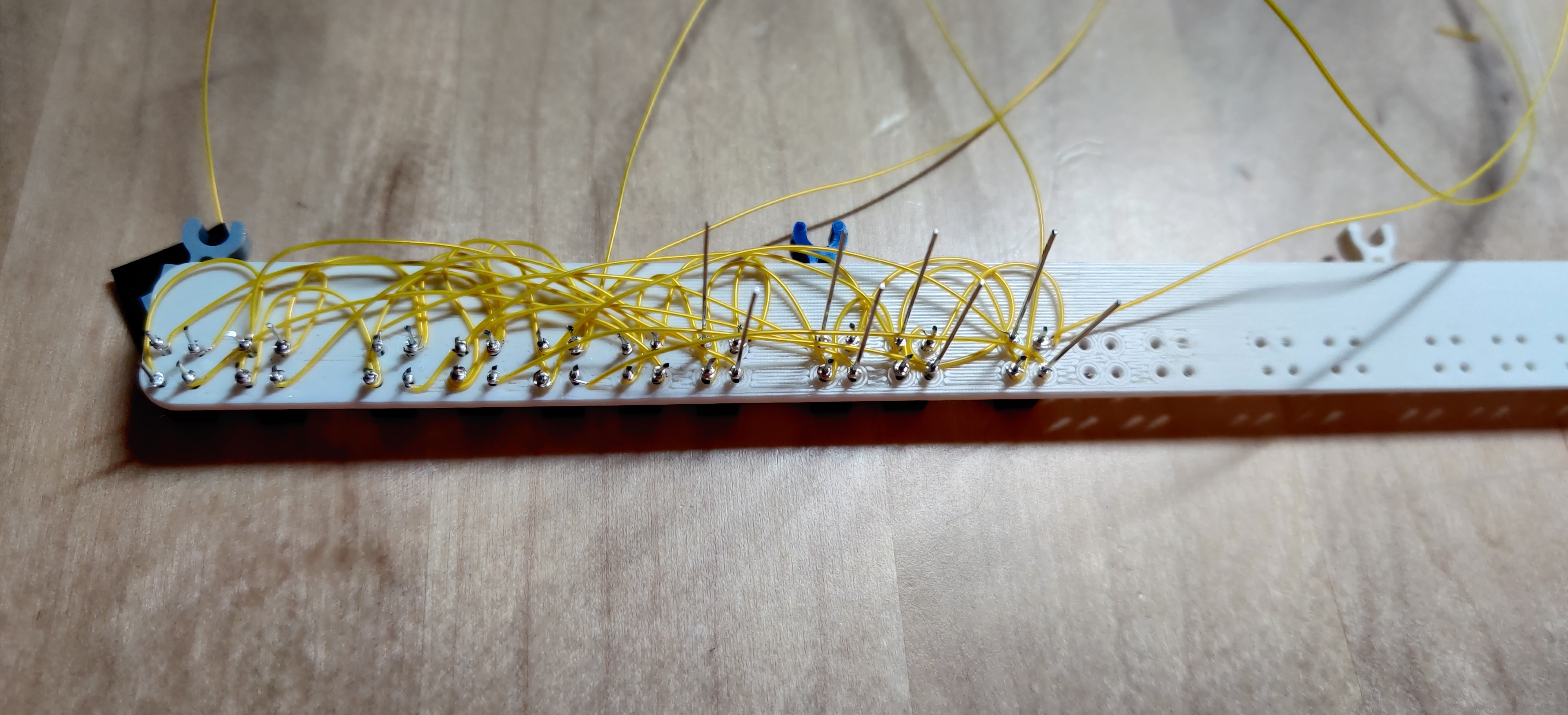 reverse side of the 29×2 rectangle, with 10 sensors inserted
into their holes from the front, and many thin electrical
wires, insulated in yellow plastic, connecting some of their
pins